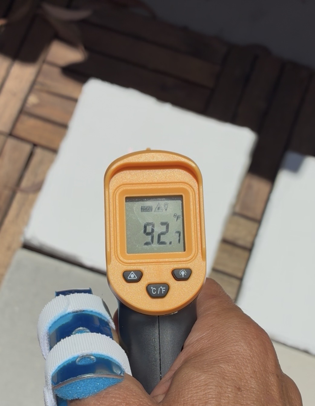 Infrared thermometer reading 92.7°F on a CoolCrete treated concrete panel in full sun